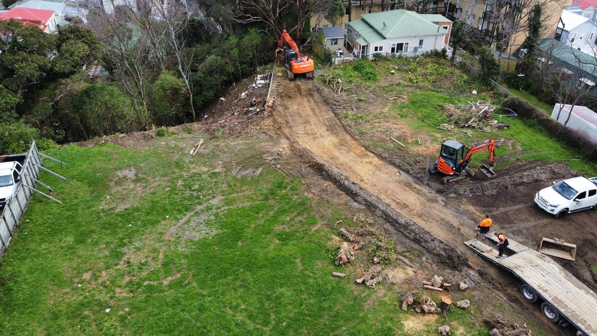 Aerial view of excavators cutting an access track across a grassed residential section
