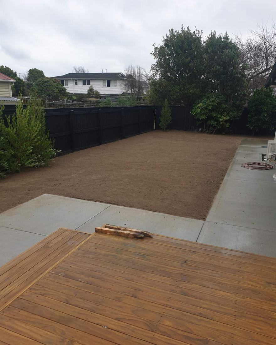 Levelled section with a new concrete path and timber deck inside a fenced backyard