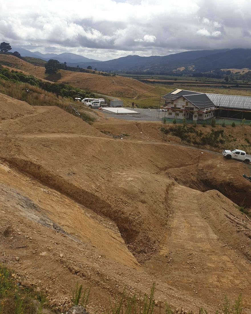 Large earthworks cuts on a hillside above a valley with houses and farmland