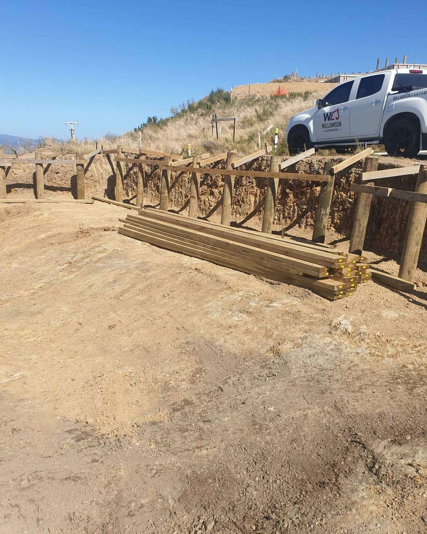 Timber post and rail barrier along a hilltop earthworks site, with a company ute parked beside it