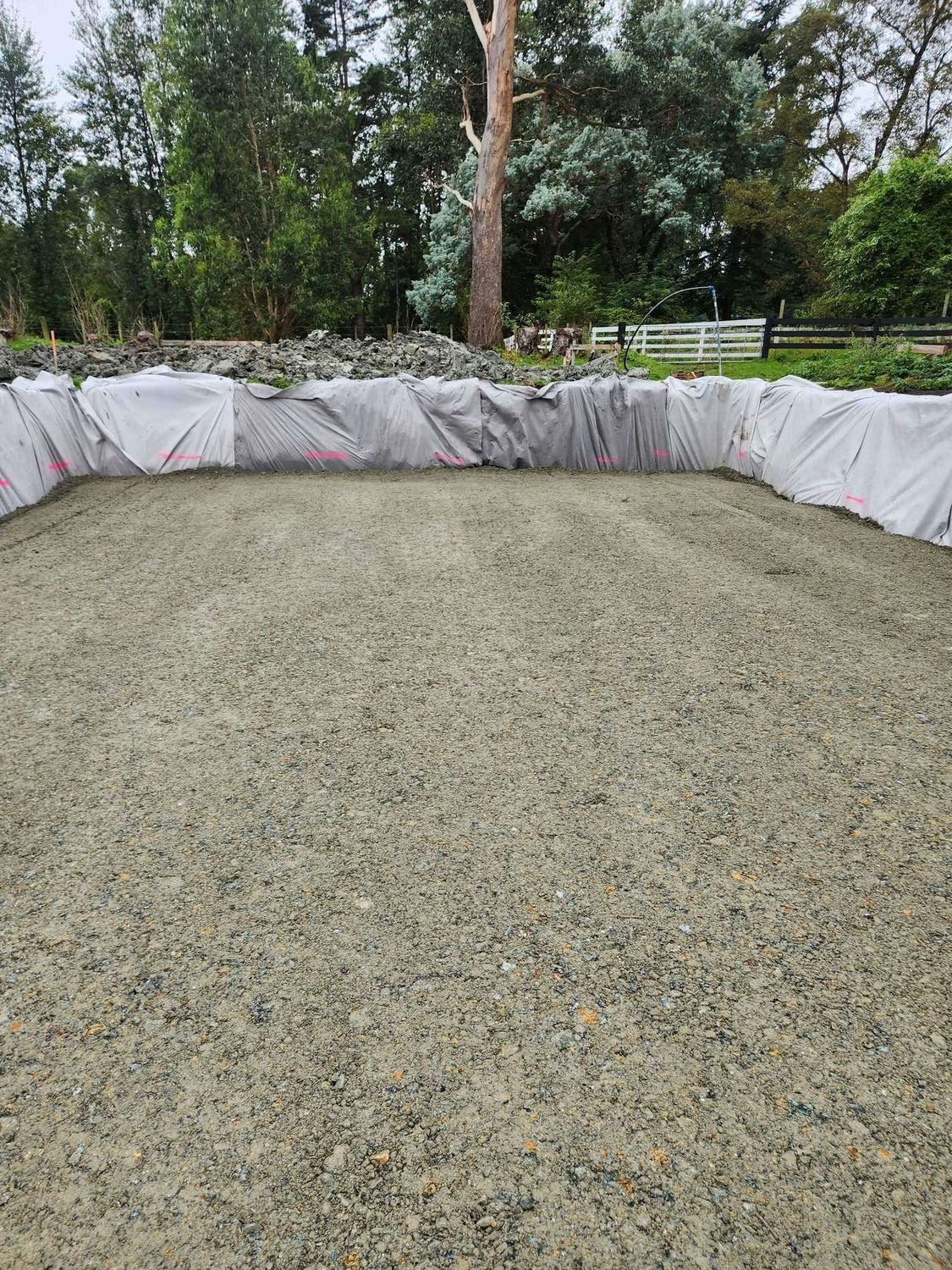 Compacted gravel pad inside an excavation lined with white geotextile