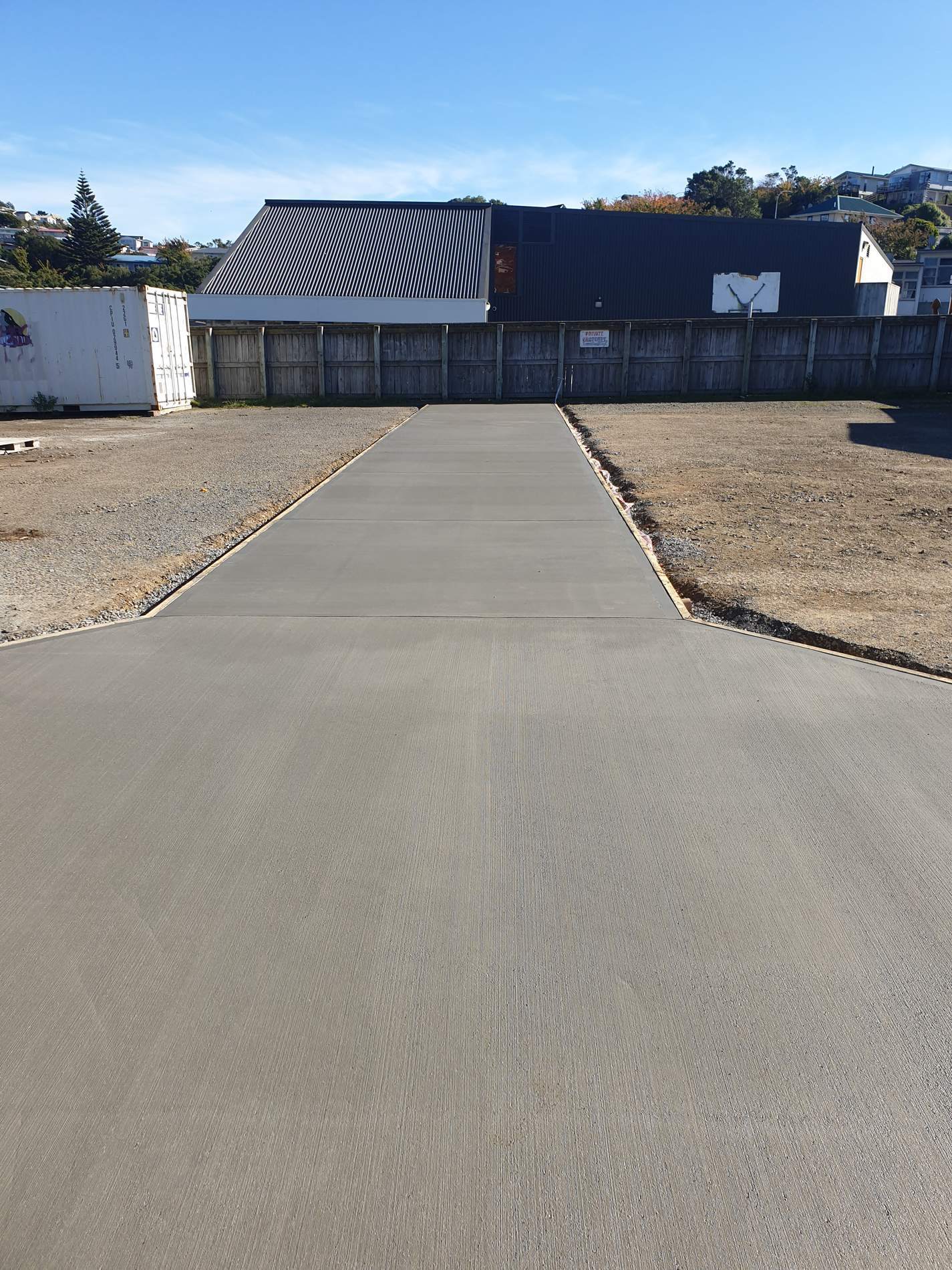 Newly poured concrete accessway running between two gravel yards