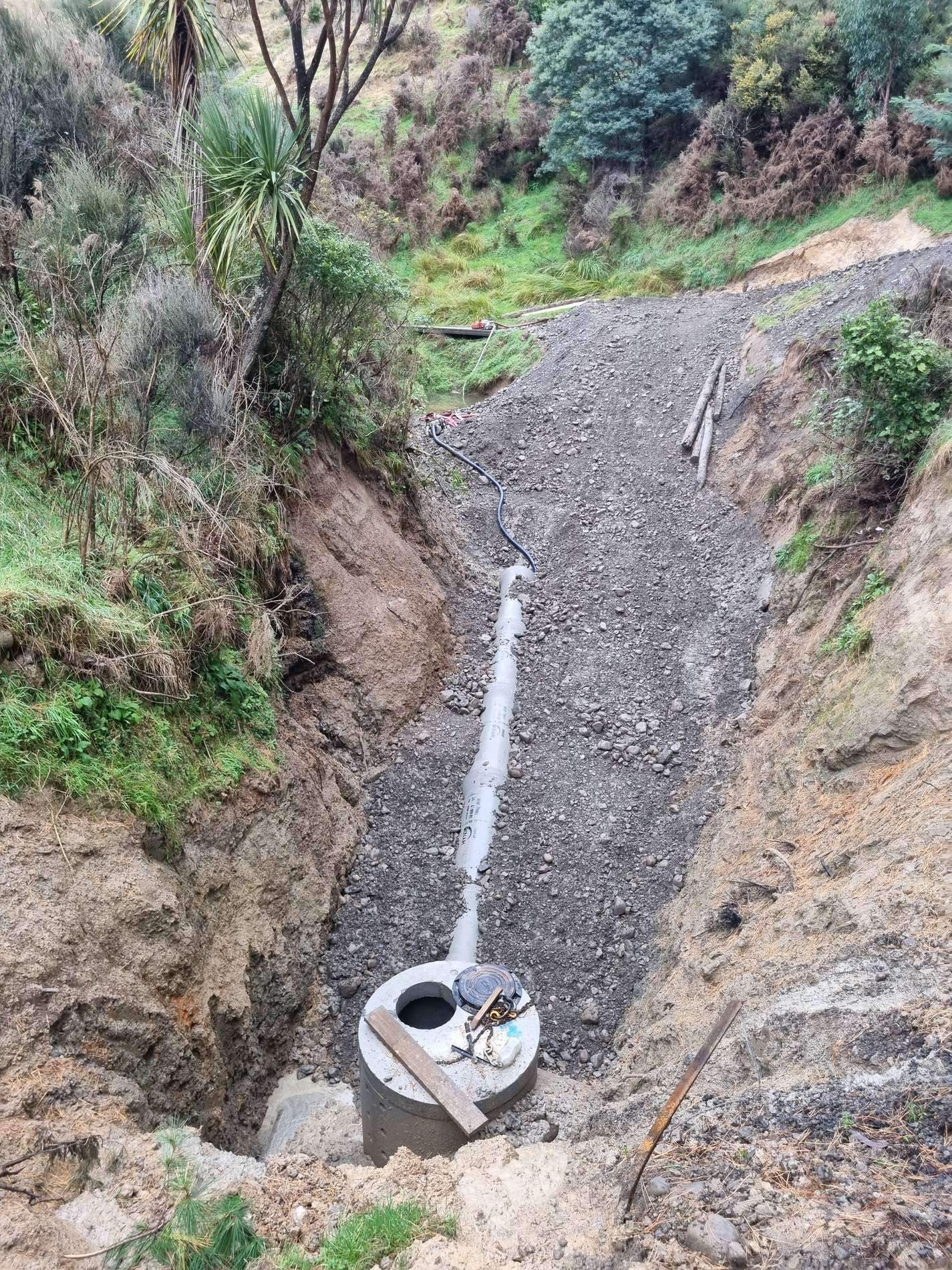 Drain line laid down an excavated gully to a concrete manhole