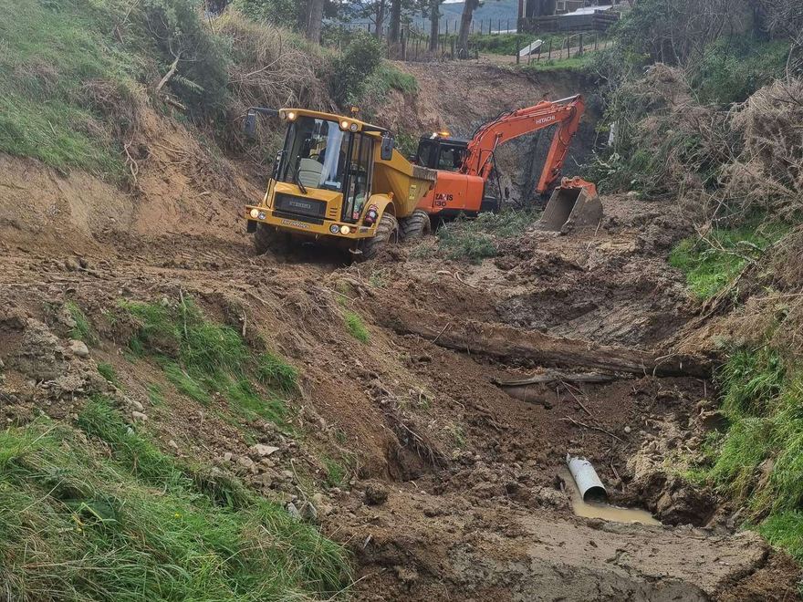 Loader and excavator clearing a stream gully around a culvert pipe